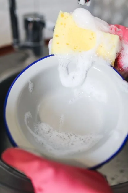 Pièce épurée avec une personne nettoyant une chaise à l’aide d’une éponge et d’un produit nettoyant.